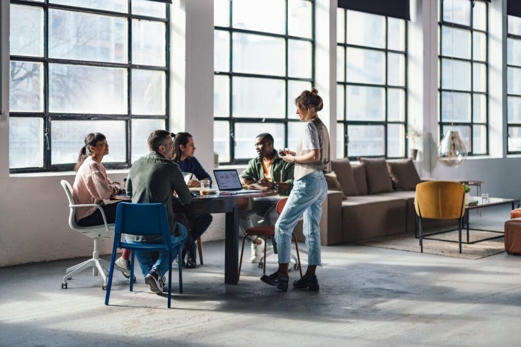 A group of young professionals collaborating around a table in a modern office setting.